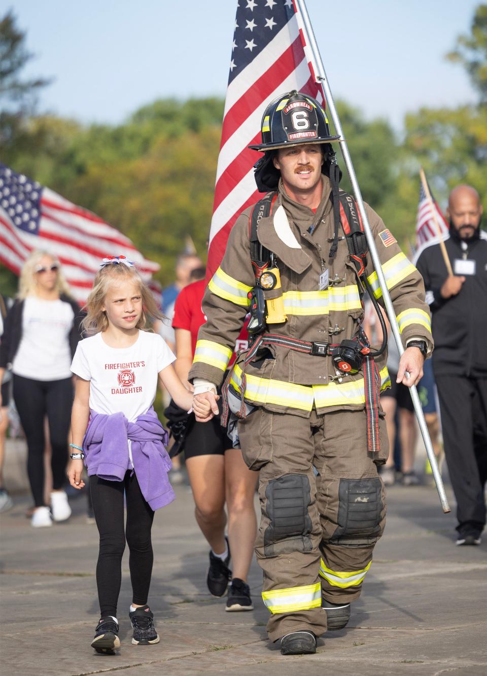 Kyle Milligan of the Arrowhead Fire Department in Gnadenhutten walks with his daughter Meleah, 8, at the 9/11 Memorial Stair Climb on Monday at the McKinley National Memorial in Canton.