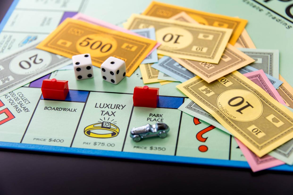 Monopoly board game with the car piece on Park Place with hotel with money and both dice on the board