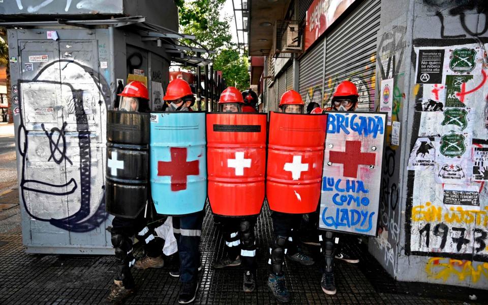 Medical volunteers take cover from water cannons during a protest against Chilean President Sebastian Pinera in Santiago on October 23, 2020, ahead of Sunday's referendum - AFP