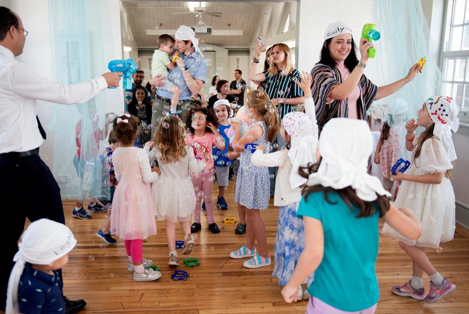 New Synagogue Family Engagement director Emily Aronoff, right, and Rabbi Barak Bar-Chaim, left, lead the congregation's Passover Story and Song on Sunday.