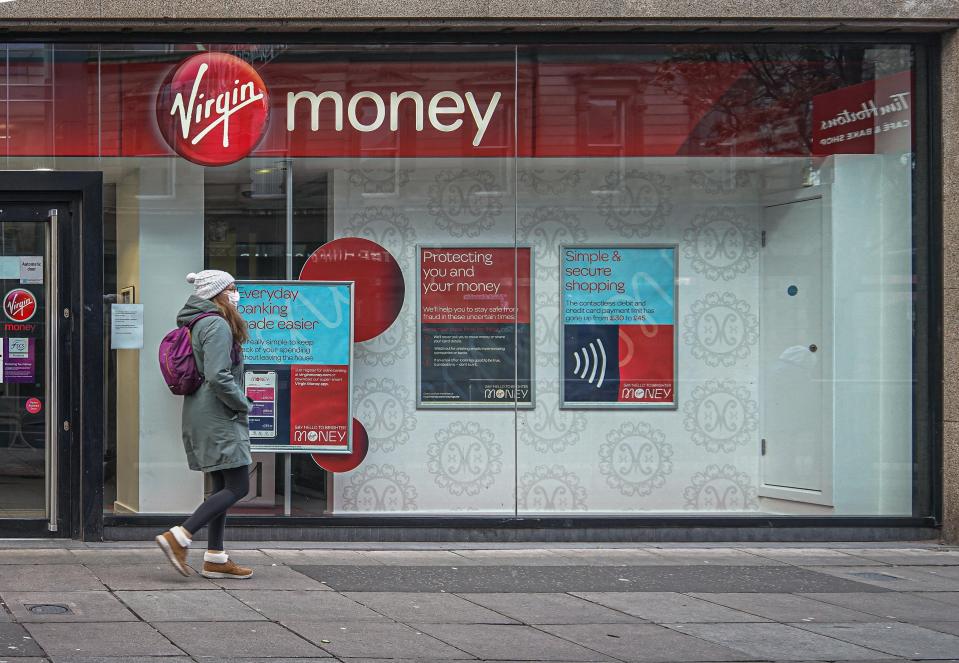 BELFAST, ANTRIM, UNITED KINGDOM - 2020/12/06: A woman wearing a face mask as a precaution against the spread of covid-19 passing by the Virgin Money Bank. (Photo by Michael McNerney/SOPA Images/LightRocket via Getty Images)