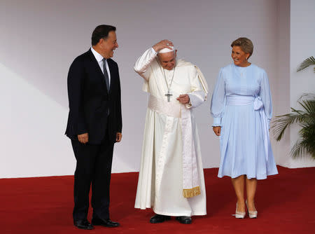 Pope Francis adjusts his skullcap flanked by Panama President Juan Carlos Varela and First Lady Lorena Castillo after arriving at Tocumen International airport for World Youth Day in Panama City, Panama January 23, 2019. REUTERS/Carlos Jasso