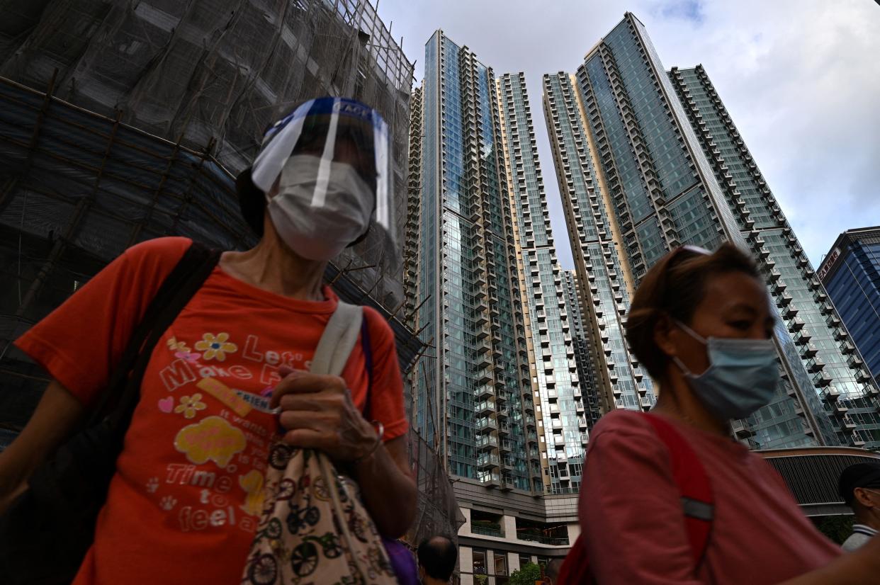 Pedestrians walk past the Grand Central residential building complex in Hong Kong on 28 May 2021, where a $1.4m one-bedroom apartment has been offered for a lucky draw's grand prize for which all Hong Kong residents aged 18 and above who have received both doses of the Covid-19 vaccines will be eligible to register (AFP via Getty Images)