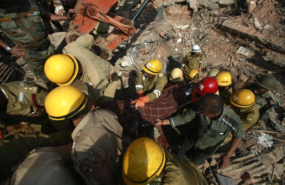 Rescue workers carry the body of a victim amid the debris of a building that collapsed in Canacona, a city about 70 kilometers (44 miles) from Goa state capital Panaji, India, Sunday, Jan. 5, 2014. A five-story building under construction in the southern Indian state of Goa collapsed on Saturday, killing at least a dozen people and leaving dozens more feared trapped under the rubble, police said. (AP Photo/Rafiq Maqbool)