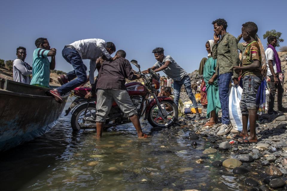 Tigray refugees who fled the conflict in the Ethiopia's Tigray arrive with their motorcycle on the banks of the Tekeze River on the Sudan-Ethiopia border, in Hamdayet, eastern Sudan, Tuesday, Dec. 1, 2020. (AP Photo/Nariman El-Mofty)