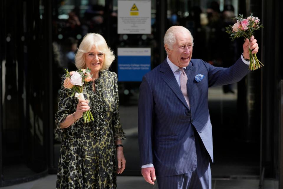 El rey Carlos III y la reina Camila sostienen las flores que les regalaron al marcharse tras la visita del martes (AP)