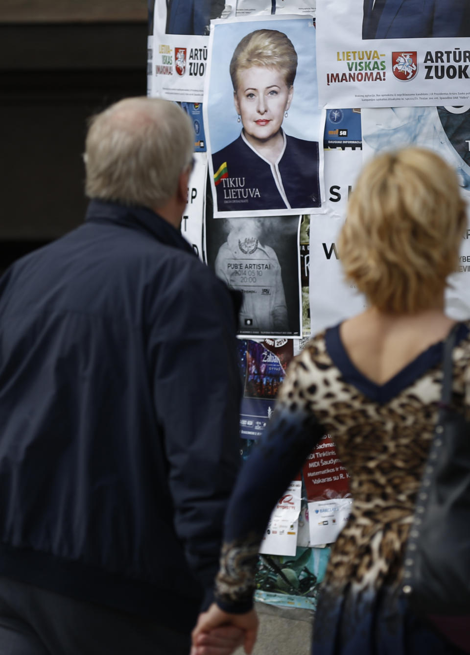 A local resident walks by an election poster showing Lithuania's President Dalia Grybauskaite, a presidential candidate, in Vilnius, Lithuania, Friday, May 9, 2014. The poster reads " I believe in Lithuania" . Lithuanians will ballot Sunday, May 11, in a first round of presidential elections. (AP Photo/Mindaugas Kulbis)