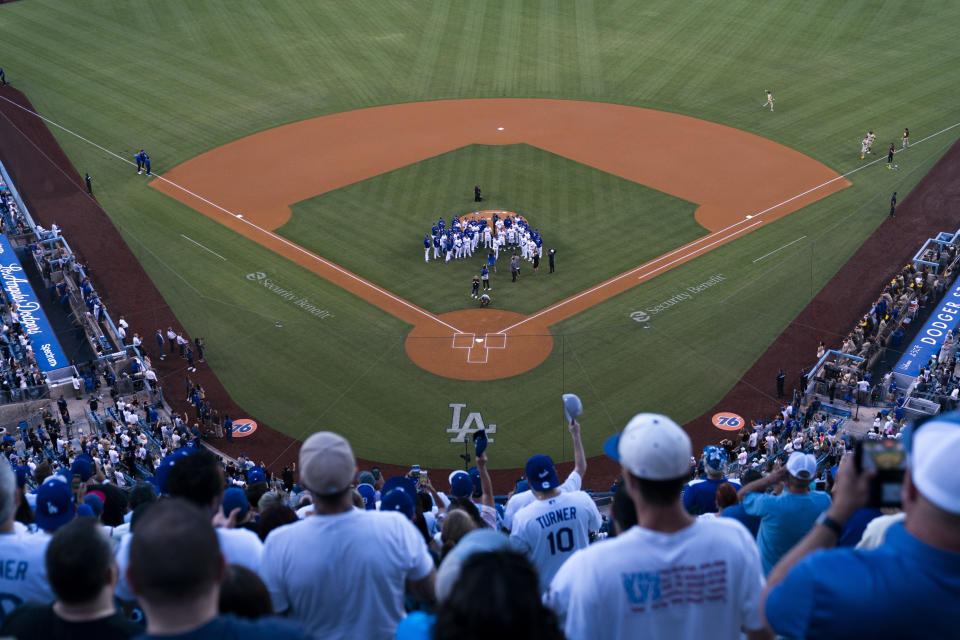 Los Angeles Dodgers players and coaches gather around the mound during a tribute for late broadcaster Vin Scully before the team's baseball game against the San Diego Padres on Friday, Aug. 5, 2022, in Los Angeles. (AP Photo/Jae C. Hong)