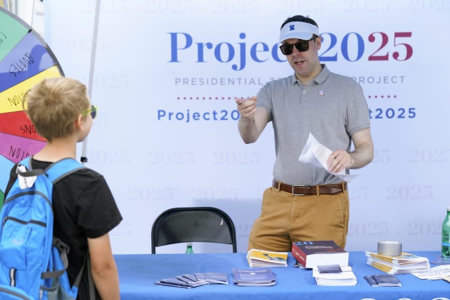 Spencer Chretien, right, talks to a young fairgoer at the Project 2025 tent at the Iowa State Fair, Aug. 14, 2023, in Des Moines, Iowa. (AP Photo/Charlie Neibergall)