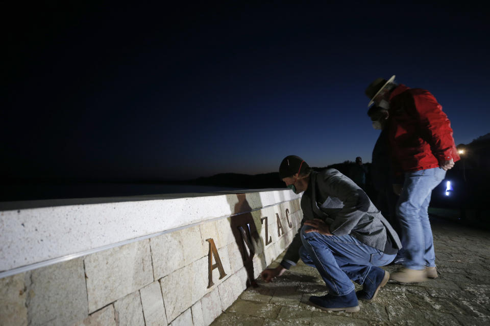 Employees of a local tourism company leave flowers at the Anzac Cove beach memorial in Gallipoli peninsula, the site of World War I landing of the ANZACs (Australian and New Zealand Army Corps) on April 25, 1915, in Canakkale, Turkey, early Saturday, April 25, 2020. The dawn service ceremony and all other commemorative ceremonies honoring thousands of Australians and New Zealanders who fought in the Gallipoli campaign of World War I on the ill-fated British-led invasion, were cancelled this year due to the new coronavirus pandemic. (AP Photo/Emrah Gurel)