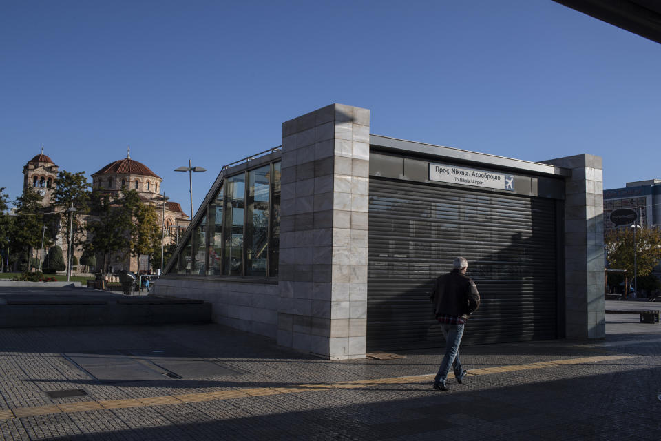 A man walks next the shuttered entrance of a metro station in the Egaleo suburb of Athens during a 24-hour strike, on Thursday, Nov. 26, 2020. Civil servants in Greece have walked off the job in a 24-hour strike expected to disrupt public transport and services, on a variety of demands, including better workplace protections against the coronavirus. (AP Photo/Petros Giannakouris)