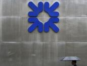 A man shelters under an umbrella as he walks past a branch of the Royal Bank of Scotland in the City of London September 17, 2013. REUTERS/Stefan Wermuth