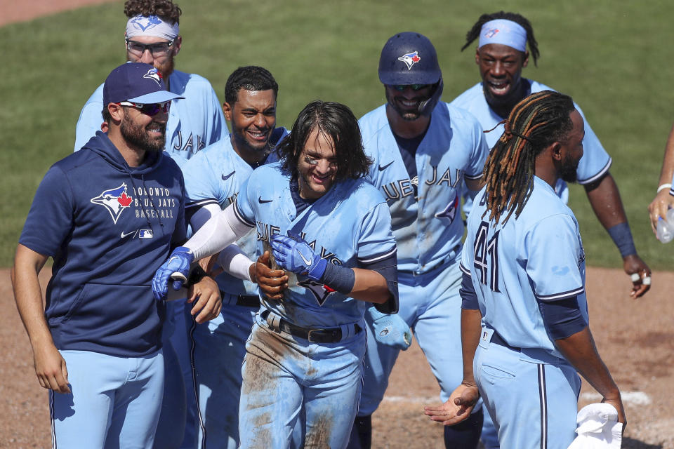 Members of the Toronto Blue Jays celebrate with Bo Bichette, center, after his game-winning home run against the New York Yankees during the ninth inning of a baseball game Wednesday, April 14, 2021, in Dunedin, Fla. The Blue Jays won 5-4. (AP Photo/Mike Carlson)