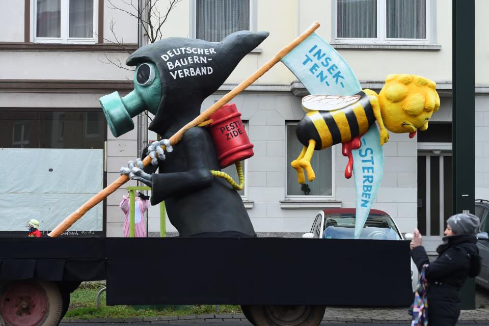 <p>A carnival float, depicting a grim reaper killing a bee, is pictured during a carnival parade on Rose Monday on Feb. 12, 2018 in Duesseldorf, western Germany. The writings read “German farmers association” (L) and “insects are dying” (R). Germany. (Photo: Patrik Stollarz/Getty Images) </p>