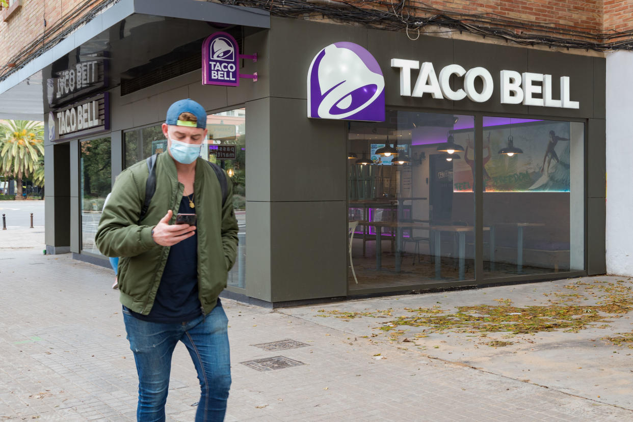 A man wearing a face mask walks past a fast food restaurant Taco Bell. (Photo by Xisco Navarro/SOPA Images/LightRocket via Getty Images)