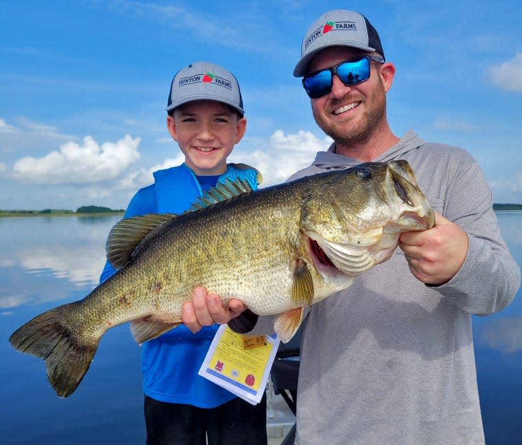 Jackson Rayburn, 11, of Plant City, smiles as his father, Jake Rayburn, shows off a 9-pound bass that he caught on a live shiner while fishing at Lake Kissimmee with Jim Childress of Big Bass Bait & Tackle recently.