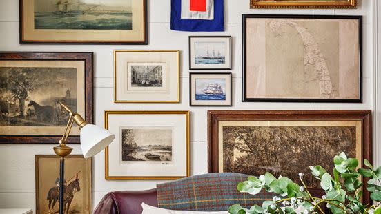 1639 cedar shake cottage of stephenie and chase watt in cape cod, massachusetts with a gallery wall behind a leather sofa