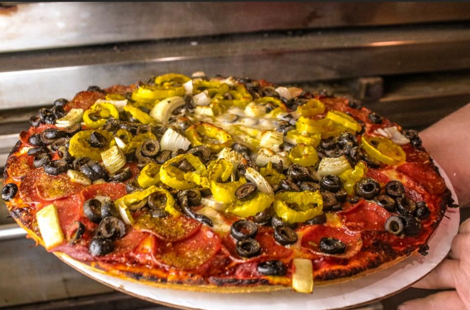 A pizza loaded with toppings is removed from the oven at The Pizza Shack in Arcadia, Okla.