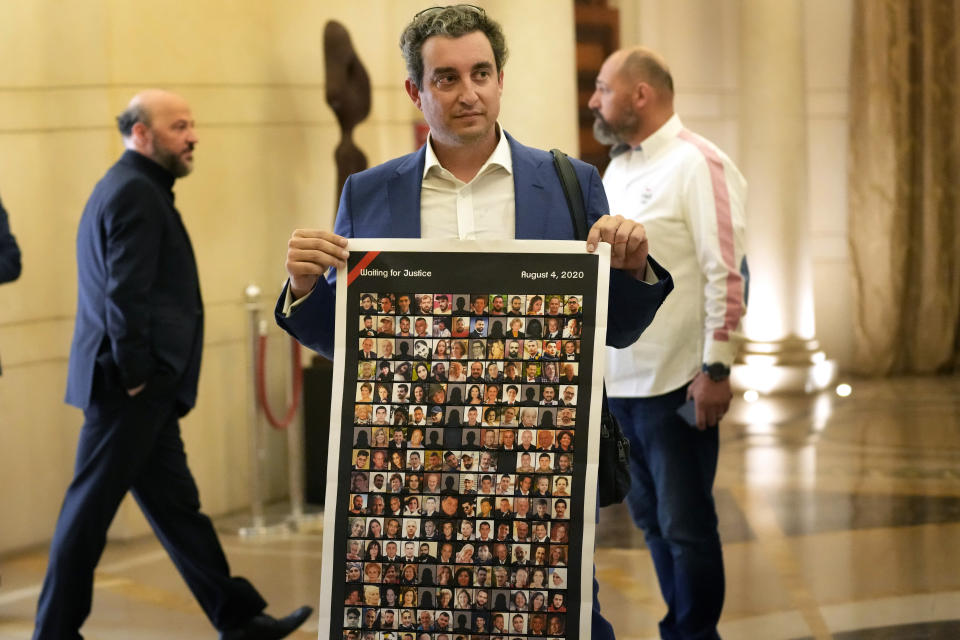 Mark Tawk, a newly elected member of parliament from the 2019 protest movement, holds a poster that shows victims of the Aug. 4, 2020 massive explosion in Beirut's port, as he arrives to attend the election of the house speaker, at the parliament building, in Beirut, Lebanon, Tuesday, May 31, 2022. Nabih Berri, Lebanon’s longtime parliament speaker, who has held the post for 30 years has been re-elected for a seventh four-year term with a slim majority despite more than a dozen new lawmakers who won seats running on a reform platform. (AP Photo/Hussein Malla)