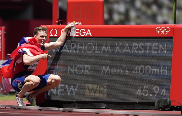 Karsten Warholm, de Noruega, celebra junto al marcador que muestra su récord mundial al ganar la medalla de oro en la final de los 400 metros con vallas masculinas.