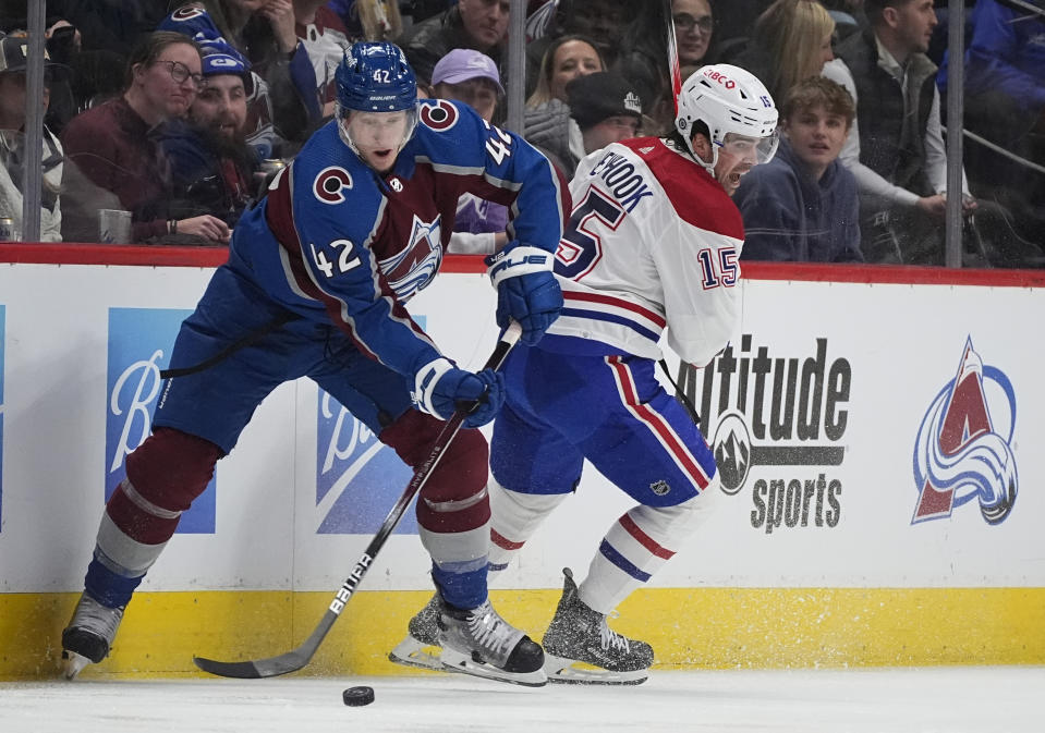 Colorado Avalanche defenseman Josh Manson, left, passes the puck as Montreal Canadiens center Alex Newhook defends in the second period of an NHL hockey game Tuesday, March 26, 2024, in Denver. (AP Photo/David Zalubowski)