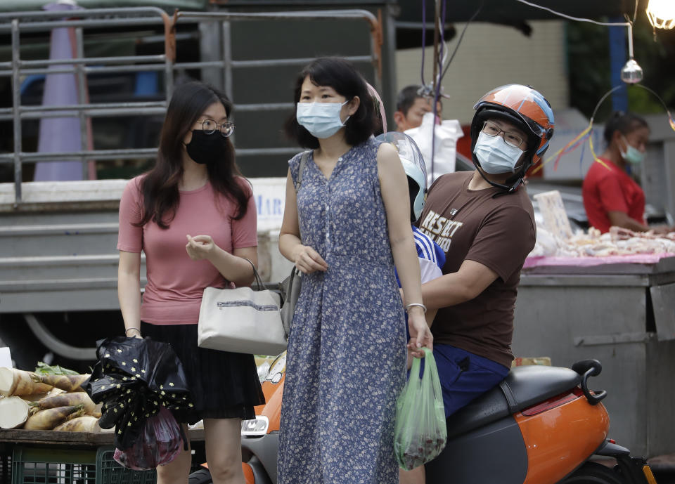 People wear face masks to help protect against the spread of the coronavirus after the COVID-19 alert rose to level 3 in Taipei, Taiwan, Friday, July 30, 2021. Taiwan's economic growth slowed to 7.5% over a year earlier in the latest quarter as anti-coronavirus controls depressed consumer spending and manufacturing. (AP Photo/Chiang Ying-ying)