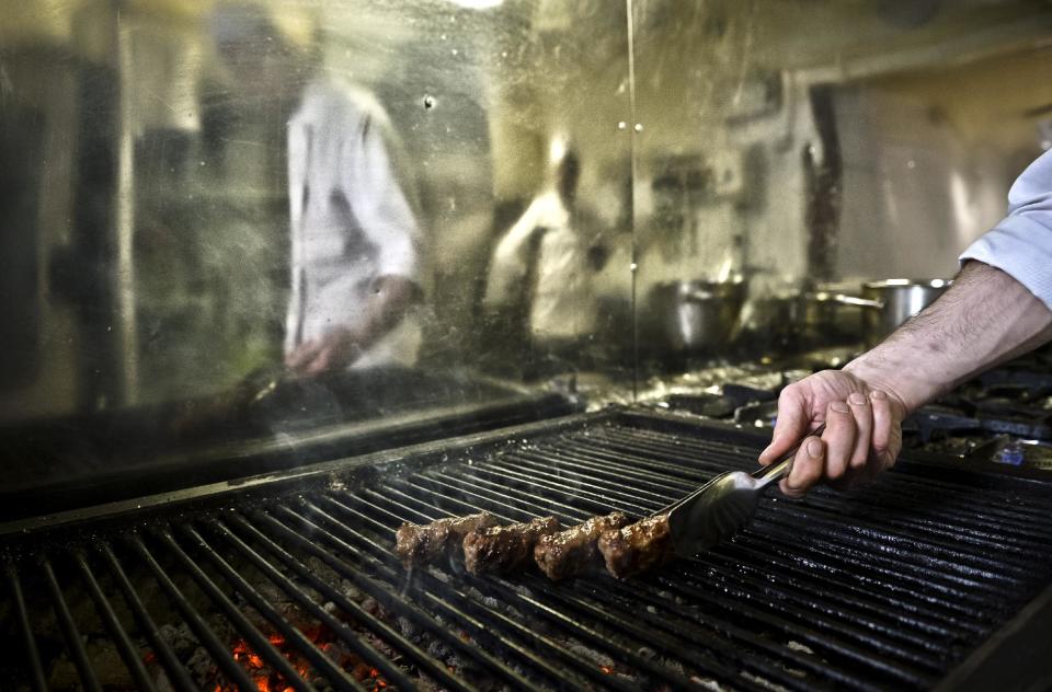 A chef grills 'mici', the Romanian version of a Turkish dish, spicy grilled sausages, popular across the Balkans, in a restaurant in Bucharest, Romania, Saturday, Feb. 15, 2014. Officials in Brussels have agreed that spicy “mici", grilled meat bullet shaped delicacies which rely on a pinch of bicarbonate of soda for their distinctive succulent flavor and puffy texture will be permitted under European Union rules, the Romanian Meat Association says.(AP Photo/Andreea Alexandru/Mediafax) ROMANIA OUT