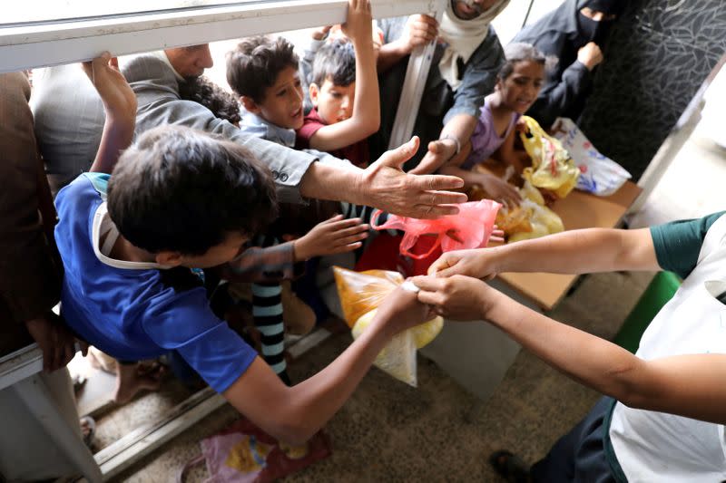 FILE PHOTO: People crowd to get food rations from a charity kitchen in Sanaa