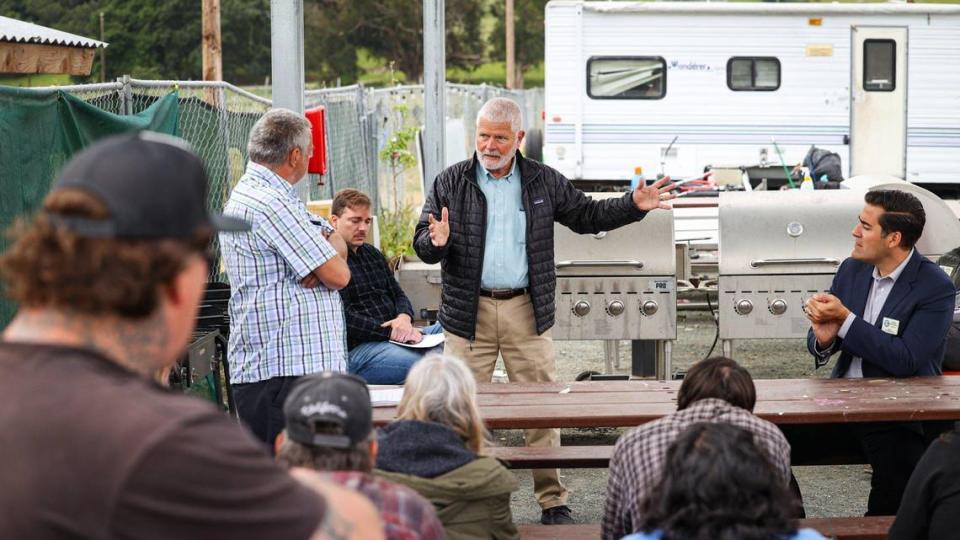 San Luis Obispo County supervisors Bruce Gibson, center, and Jimmy Paulding, seated at right, talk to residents at the Oklahoma Avenue safe parking site on April 26, 2023. Resident David Richford is standing at left.