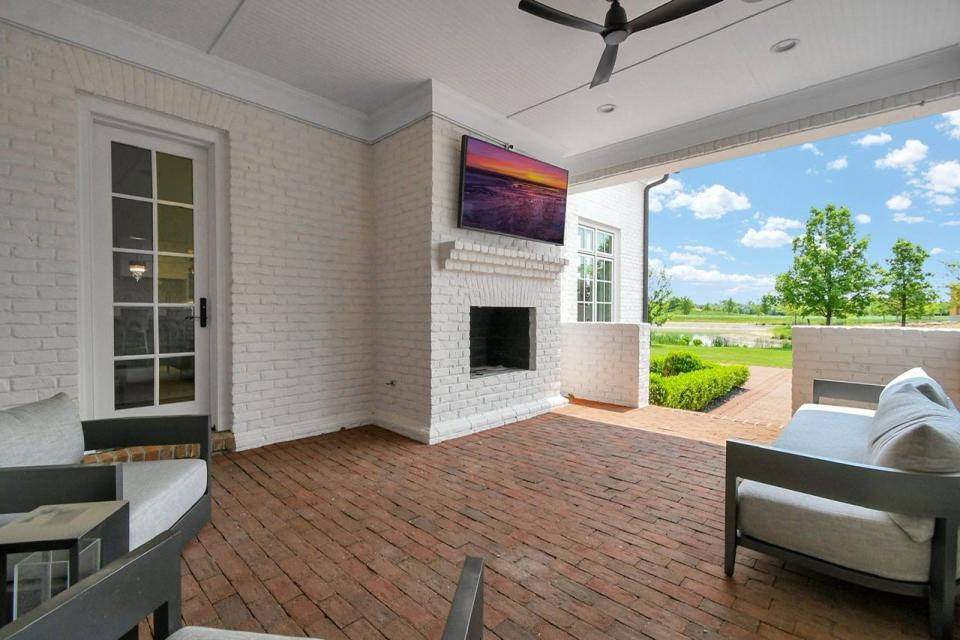 The covered rear porch of a newly listed New Albany home overlooks a pond and golf course.