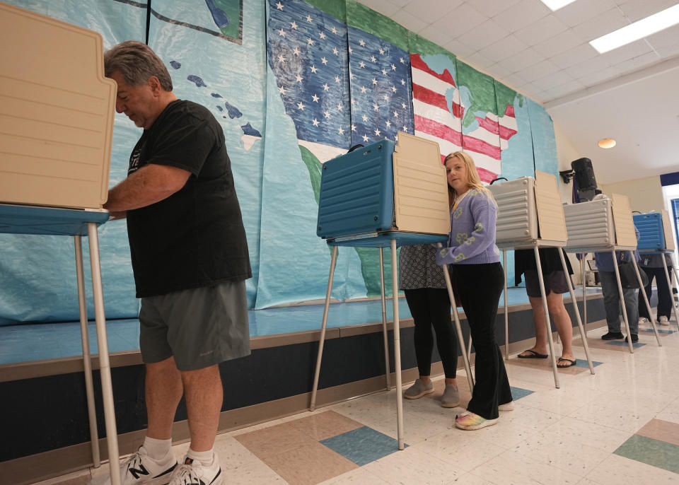 Voters cast their ballots in front of a mural at a Elementary school polling station Tuesday Nov. 7, 2023, in Midlothian, Va. (AP Photo/Steve Helber)