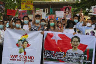 Migrant workers from Myanmar flash the three-finger protest gesture while they hold banners with images of deposed Myanmar leader Aung San Suu Kyi before participating in a march by Thai pro-democracy activists to the residence of Thai Prime Minister Prayuth Chan-ocha Sunday, Feb. 28, 2021 in Bangkok, Thailand. The group joined the march after Prayuth met with the Myanmar Foreign Minister Wunna Maung Lwin in Bangkok earlier in the week. Security forces in Myanmar have made mass arrests and appeared to use lethal force as they intensify their efforts to break up protests a month after the military staged a coup. (AP Photo/Fu Ting)