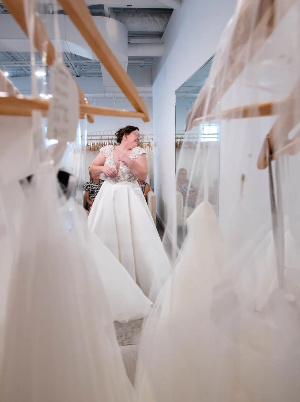 La novia Kimberly “Kiki” Waldrop, de Atmore, Alabama, mirando un vestido en el espejo mientras compra en Bliss Bridal en Fairhope, Alabama, el jueves 20 de junio de 2024.
