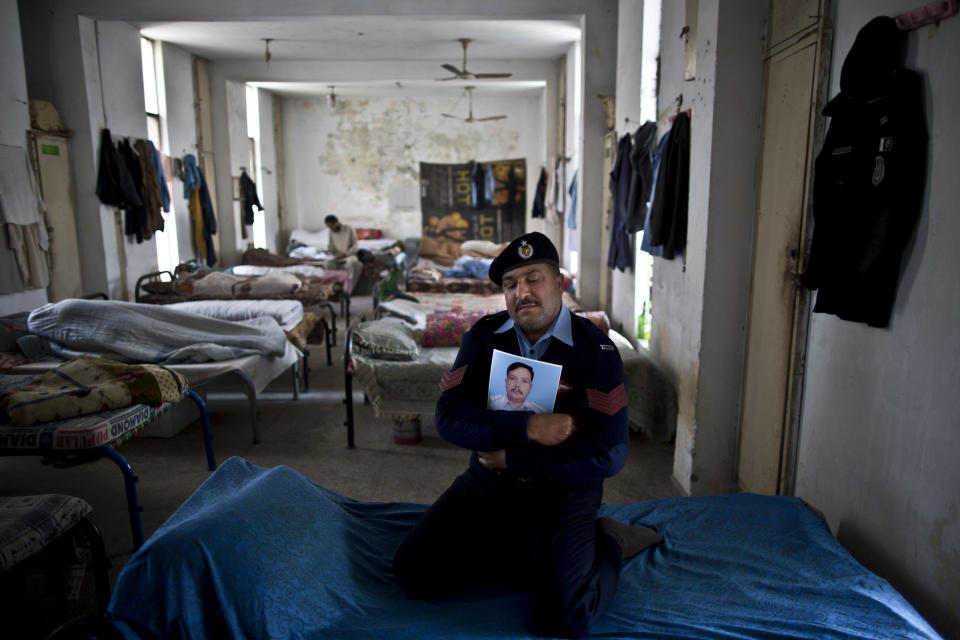 In this Wednesday, March 19, 2014 photo, Pakistani policeman, Mian Asif, 44, a colleague and best friend of former policeman, Muhammad Riaz, 46, who was one of eleven victims that was killed by suicide bombers in an attack on a court complex on the 3rd of March 2014, sits on his best friend's bed embracing his photograph, inside a police station dormitory, in Islamabad, Pakistan. "I lost part of me after Muhammad's death, he was my right arm," Mian said. (AP Photo/Muhammed Muheisen)