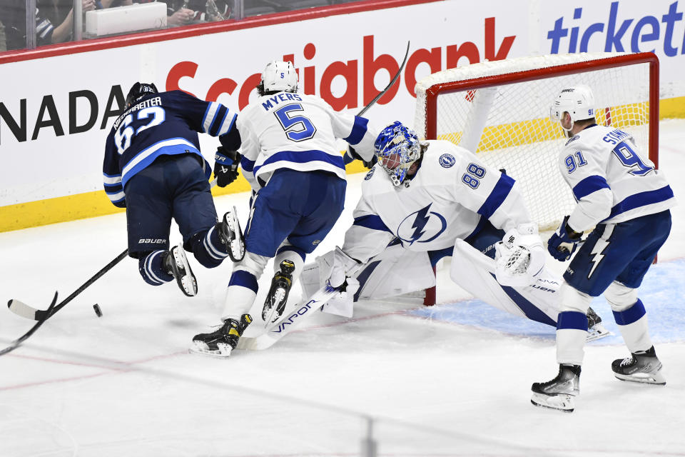 Tampa Bay Lightning goaltender Andrei Vasilevskiy (88) trips Winnipeg Jets' Nino Niederreiter (62) as Lightning's Philippe Myers (5) defends during the third period of an NHL hockey game Tuesday, Jan. 2, 2024, in Winnipeg, Manitoba. (Fred Greenslade/The Canadian Press via AP)