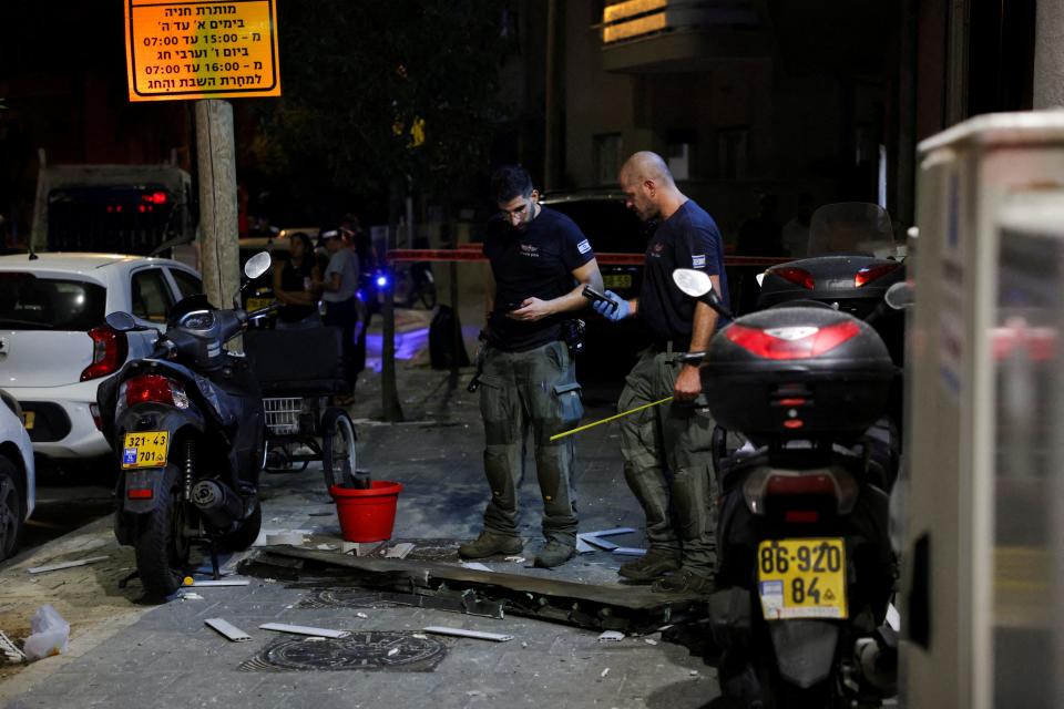 Investigators examine what, according to a police spokesperson, seems to be part of an aerial device, at the site of an explosion in Tel Aviv on July 19, 2024.