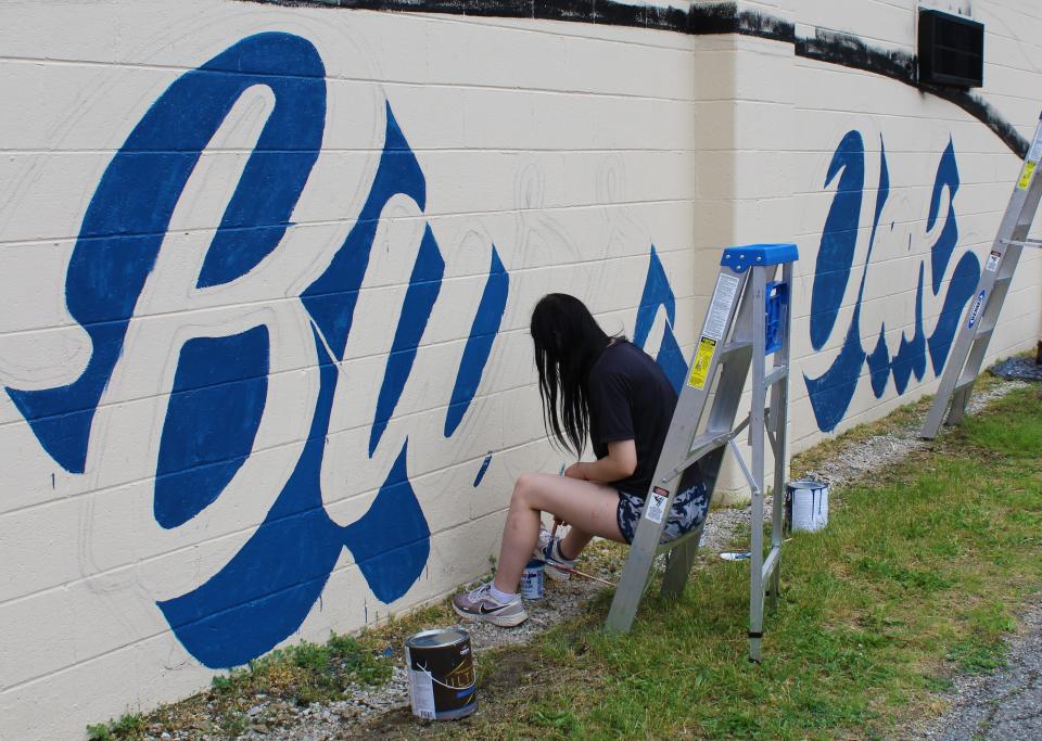 Burr Oak art student Hannah Greene and her classmates spent time the last two days of school helping to paint the mural by Heidi Wolfe going up in the village.