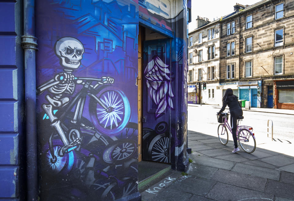 A cyclist passes a mural featuring a skeleton on a bicycle in Edinburgh as the UK continues in lockdown to help curb the spread of the coronavirus.