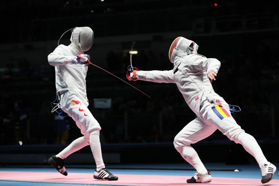 Athletes from China (left) and Romania (right) compete in men's saber fencing at the Rio Olympics.
