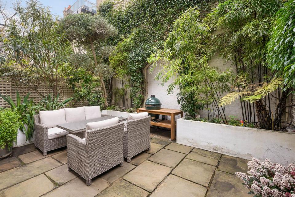 a patio with an outdoor sofa and a table and plants