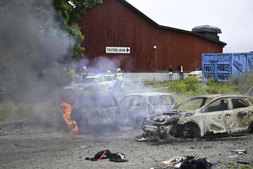 Police stand near the gutted remains of cars, at the Eritrean cultural festival "Eritrea Scandinavia" in Stockholm Thursday, Aug. 3, 2023. A violent clash at an Eritrea-themed culture festival in Sweden has caused a chaos as about a thousand anti-Eritrean government protesters stormed the outdoor festival venue throwing stones, setting fire on booths and tearing down tents. (Magnus Lejhall/TT News Agency via AP)