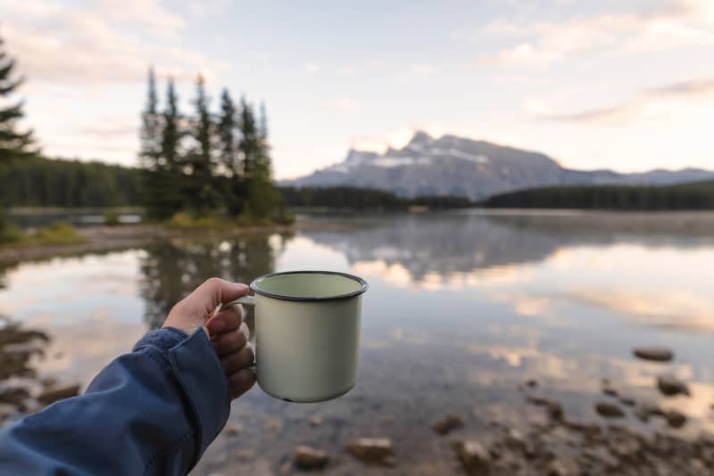 camper woman holding enamel cups at Maligne lake, Canada