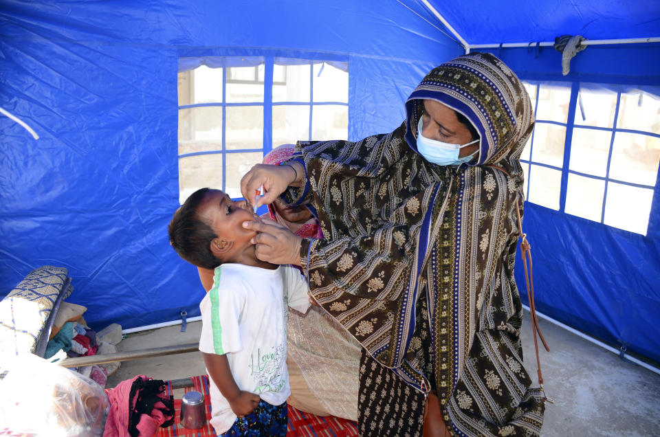 A health worker administers a polio vaccine to a child at a camp in Hyderabad, Pakistan, Tuesday, Sept. 6, 2022. In flood-stricken Pakistan where an unprecedented monsoon season has already killed hundreds of people, the rains are now threatening an ancient archeological site dating back 4,500 years, the site's chief official said Tuesday. (AP Photo/Pervez Masih)