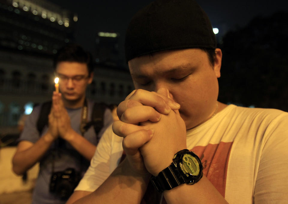 Men offer prayers during a candlelight vigil for passengers aboard a missing Malaysia Airlines plane in Kuala Lumpur, Malaysia, Monday, March 10, 2014. The search operation for the missing Malaysia Airlines Flight MH370 which has involved 34 aircraft and 40 ships from several countries covering a 50-nautical mile radius from the point the plane vanished from radar screens between Malaysia and Vietnam continues after its disappearance since Saturday. (AP Photo/Lai Seng Sin)