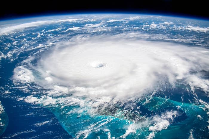 Satellite image of a massive hurricane over the ocean, showcasing a clear, spiraling eye and cloud formations. Earth’s curvature is visible