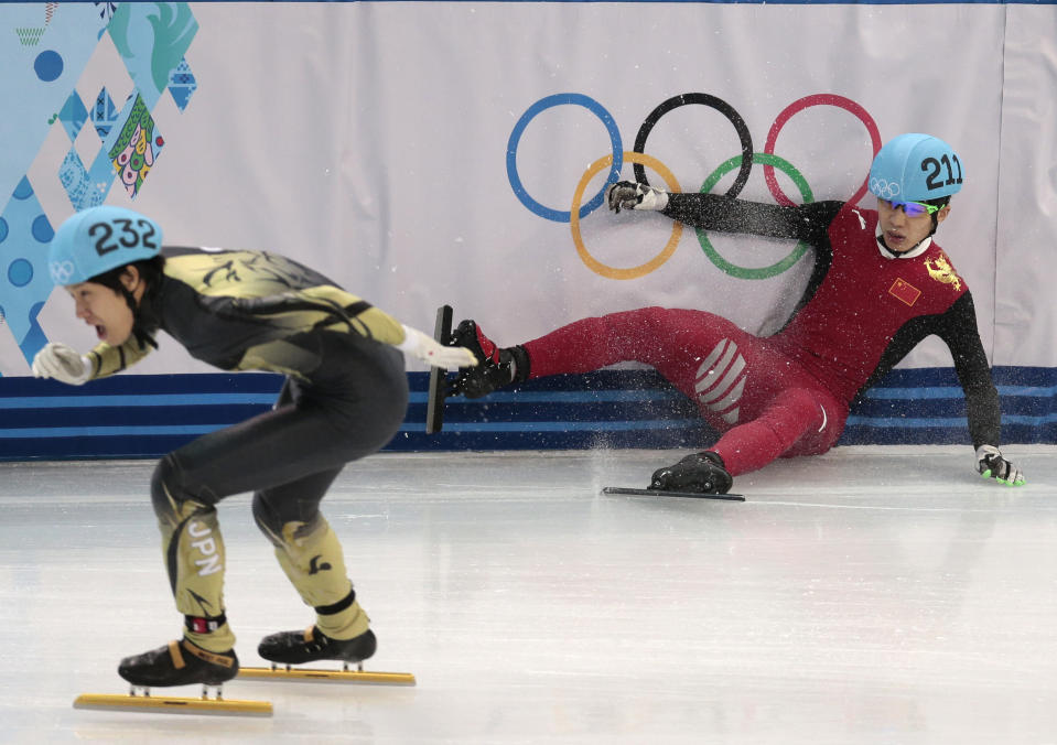 Shi Jingnan of China, right, crashes as Ryosuke Sakazume of Japan skates past in a men's 1500m short track speedskating heat at the Iceberg Skating Palace during the 2014 Winter Olympics, Monday, Feb. 10, 2014, in Sochi, Russia. (AP Photo/Ivan Sekretarev)