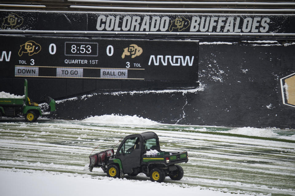 Workers clear the field at Folsom Field before Colorado's spring NCAA football game, Saturday, April 22, 2023, in Boulder, Colo., following a snowstorm. (AP Photo/David Zalubowski)