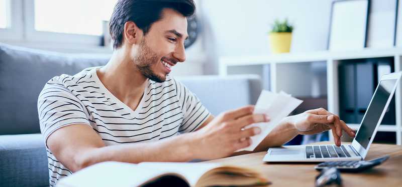 A man smiles as he pays bills online.