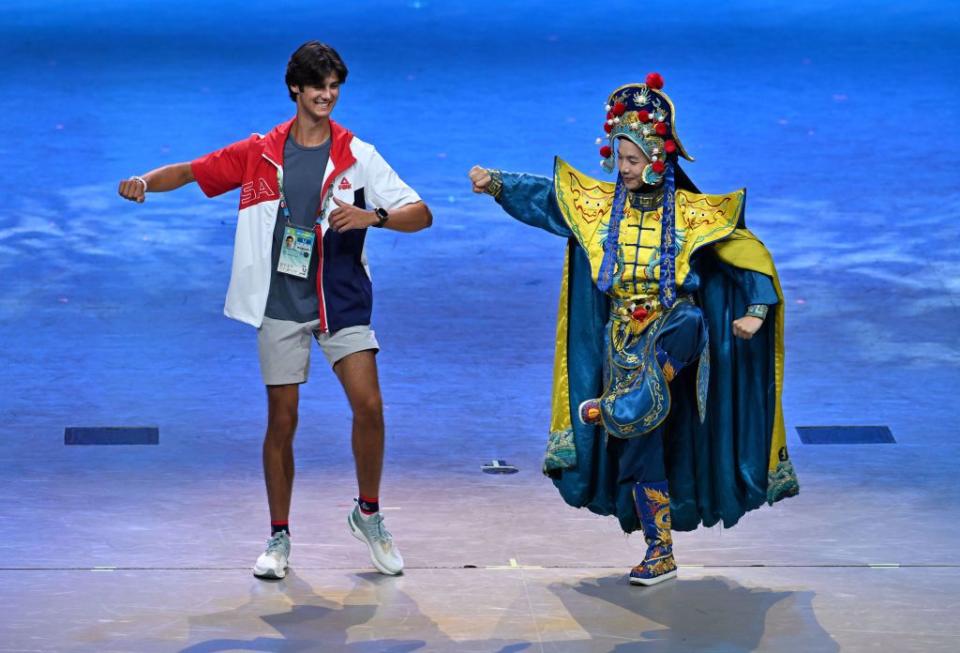 美國運動員杜恩（左）在世大運聯歡會現場與川劇演員互動。（新華社）