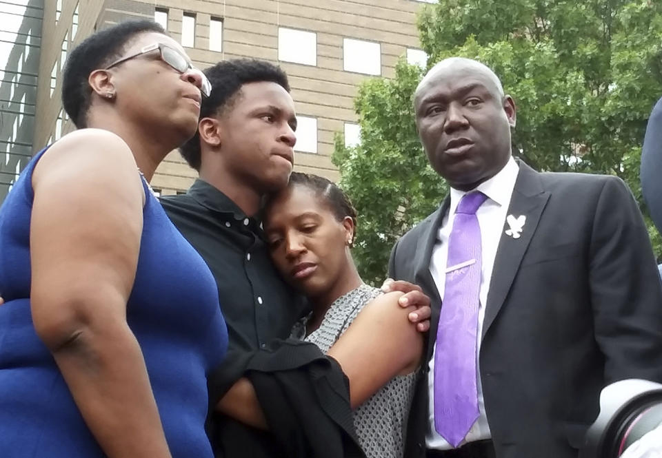 FILE - In this Sept. 10, 2018 file photo, Brandt Jean, center left, brother of shooting victim Botham Jean, hugs his sister Allisa Charles-Findley, during a news conference about the shooting of Botham Jean by Dallas Police Officer Amber Guyger, outside the Frank Crowley Courts Building in Dallas. He was joined by his mother, Allison Jean, left, and attorney Benjamin Crump, right. Guyger, who was fired soon after the shooting and charged with murder, said she mistook Jean’s apartment for her own. She was convicted in early Oct. 2019 — a rare jury decision — and sentenced to 10 years in prison. (AP Photo/Ryan Tarinelli, File)